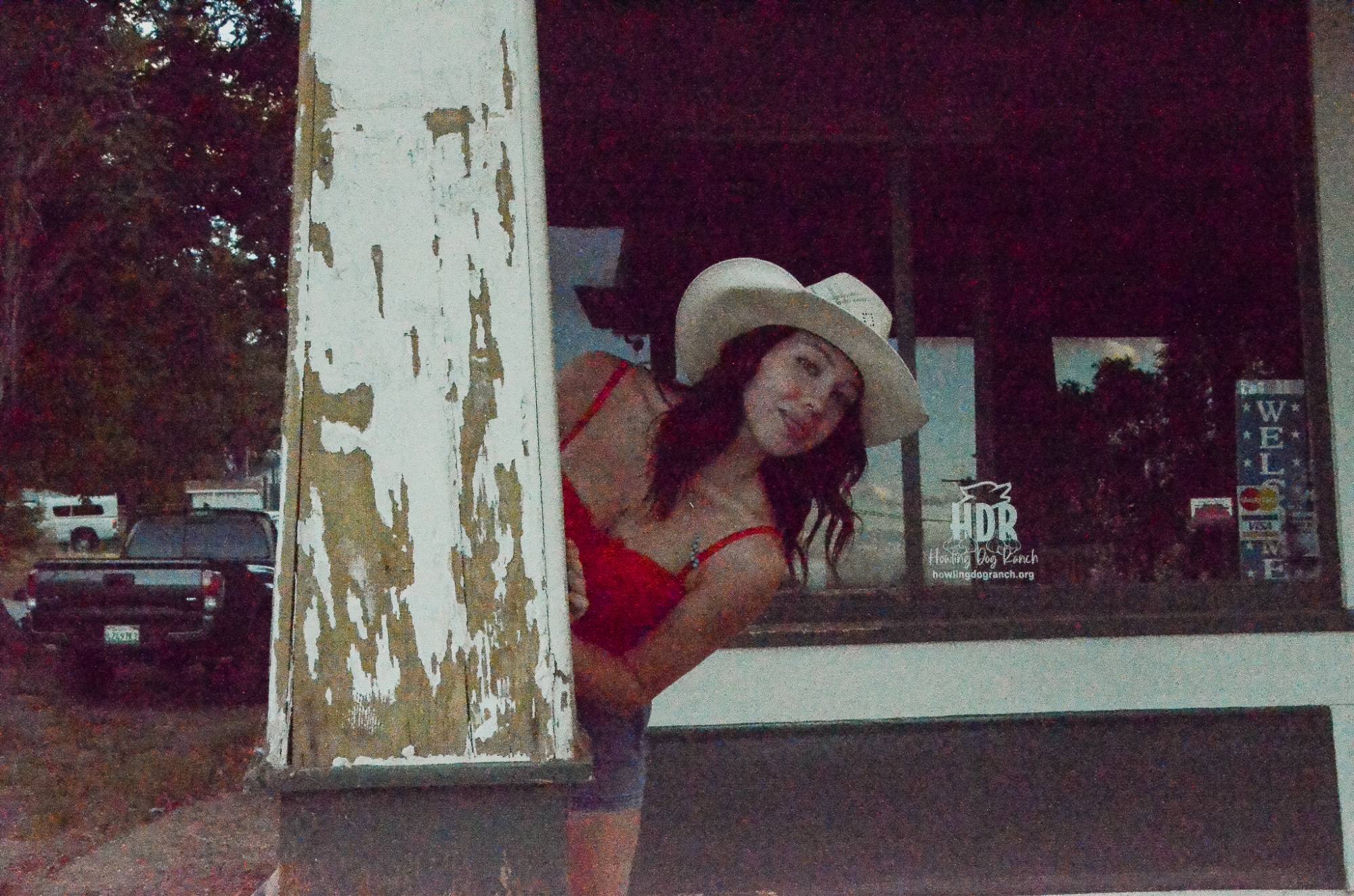 Olivia peeking out from behind a weathered white porch column