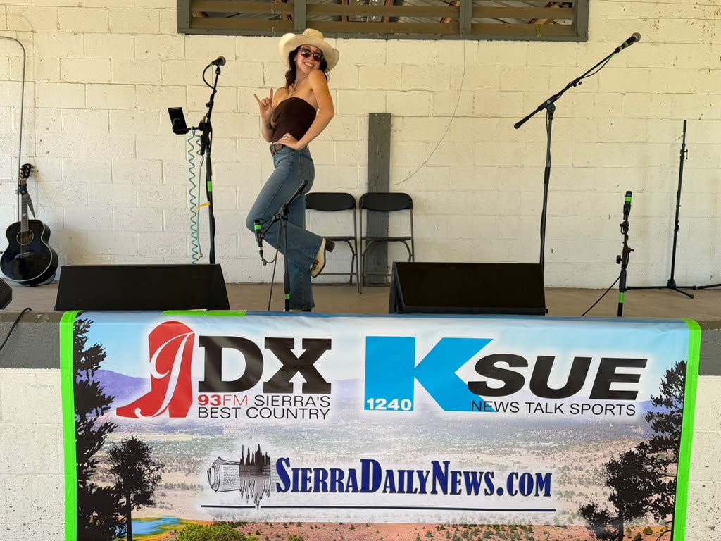 Olivia striking a pose on an outdoor stage in a cowboy hat and sunglasses